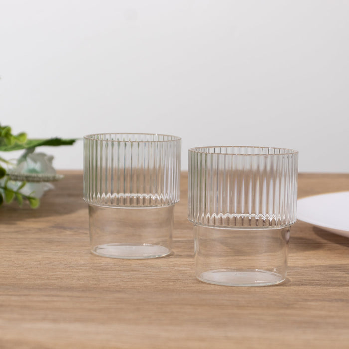Set of two ribbed glass tumblers on a wooden surface.