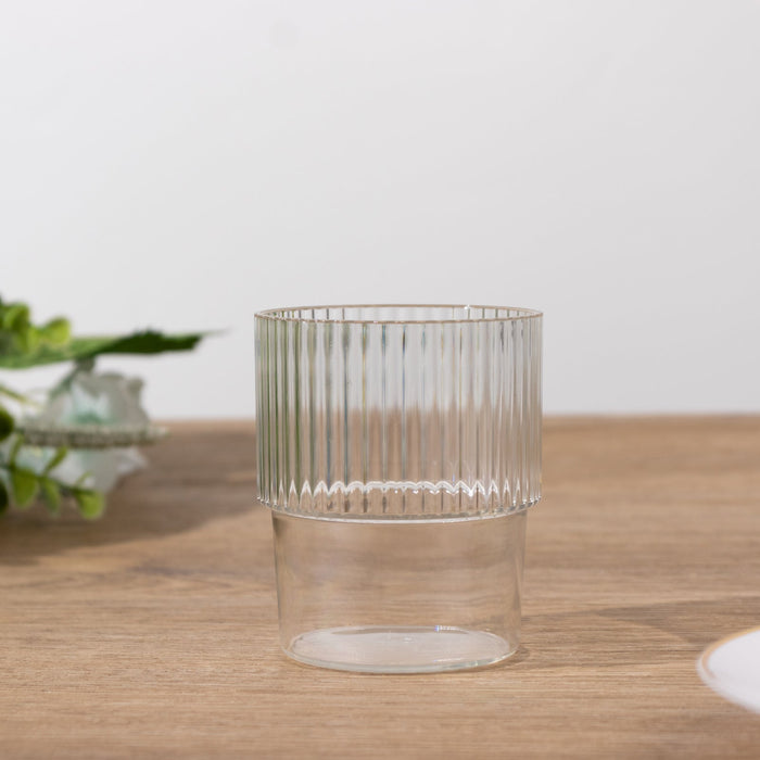 Clear ribbed glass tumbler on wooden surface.