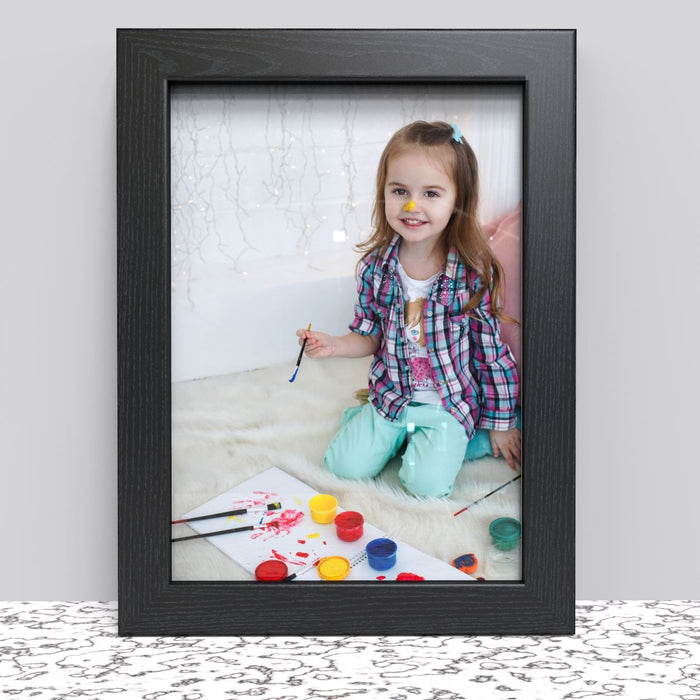 Happy child painting pictured in A4 picture frame options, showcasing creativity and fun in a stylish black frame.