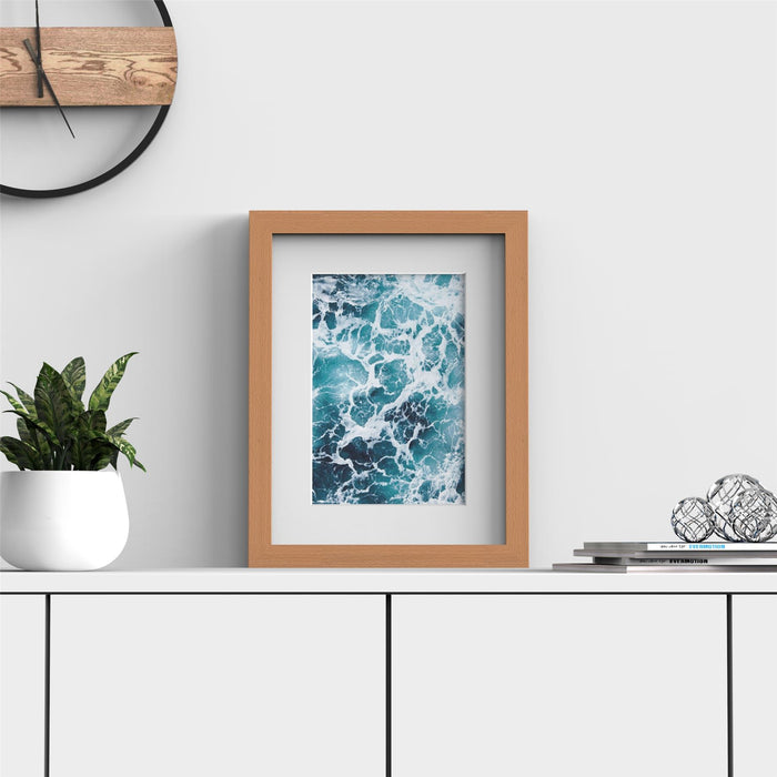 Beech picture frame with white mount showcasing an ocean wave photo on a minimalist shelf display.