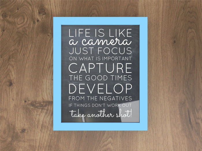 Life is like a camera print in a blue picture and poster frame on wooden background.