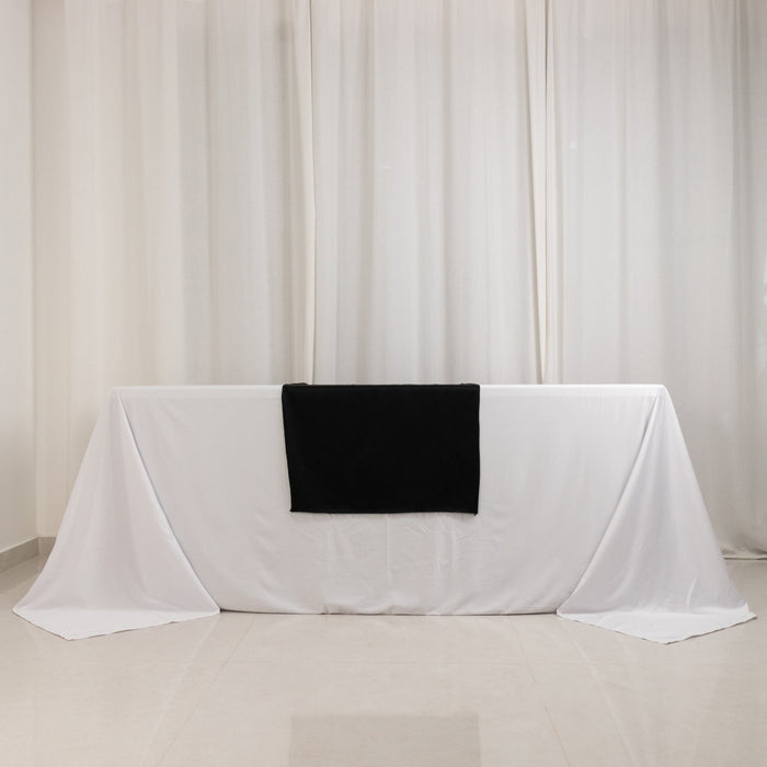 Black blanket draped on a white table against a light backdrop.
