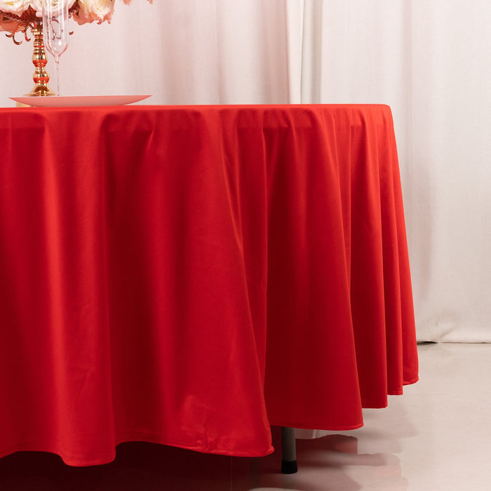 Red tablecloth draped over a round table in a styled setting.