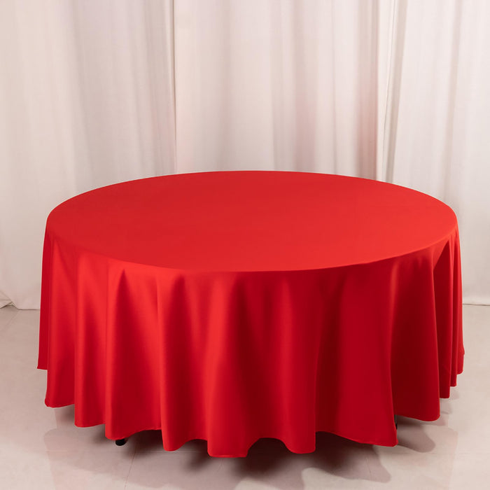 Red round tablecloth on a circular table against a plain backdrop.