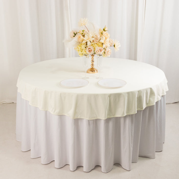 Elegant round table with cream and white tablecloth, adorned with floral centerpiece.